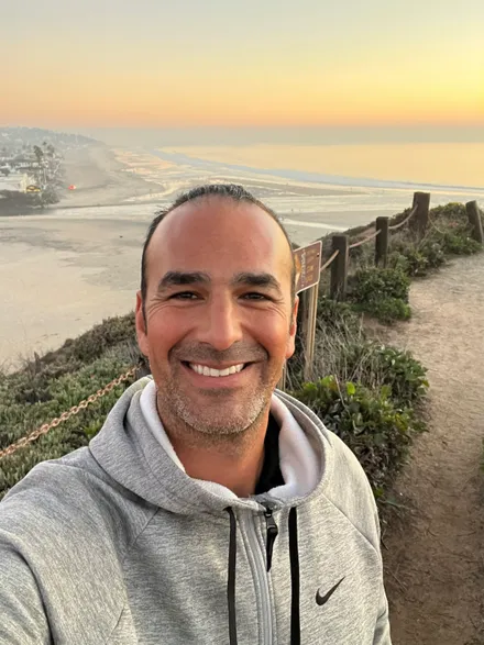 Alan Seideman, outdoors on a bluff above the beach at sunset